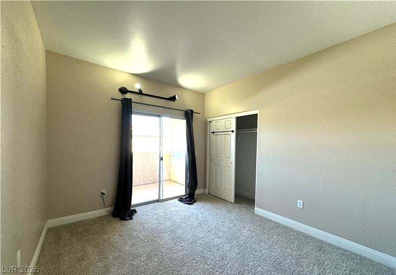 Sliding glass doors open to a private balcony from this carpeted bedroom.