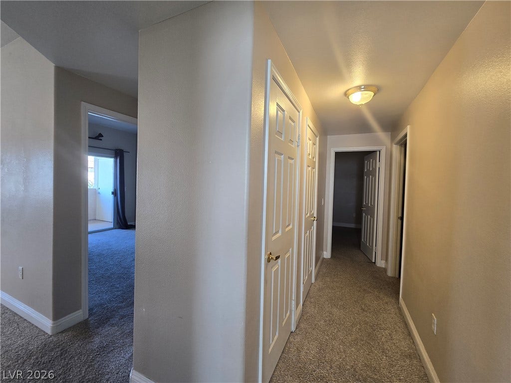 A classic hallway layout leads to multiple rooms with wall-to-wall carpeting.