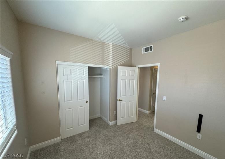 A spacious bedroom with plush carpeting, a built-in closet, and tall ceilings.