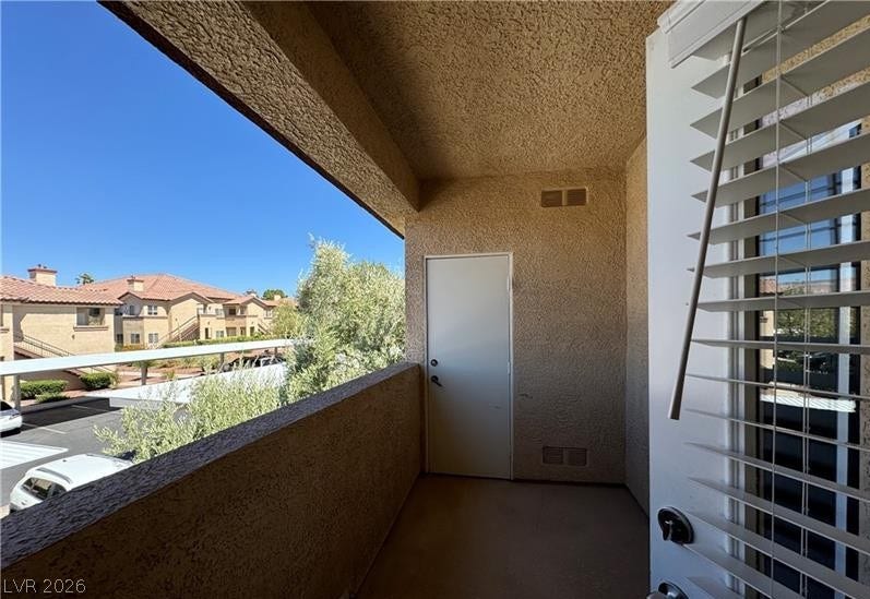 An inviting covered balcony features structured stucco walls and overlooking neighborhood views.