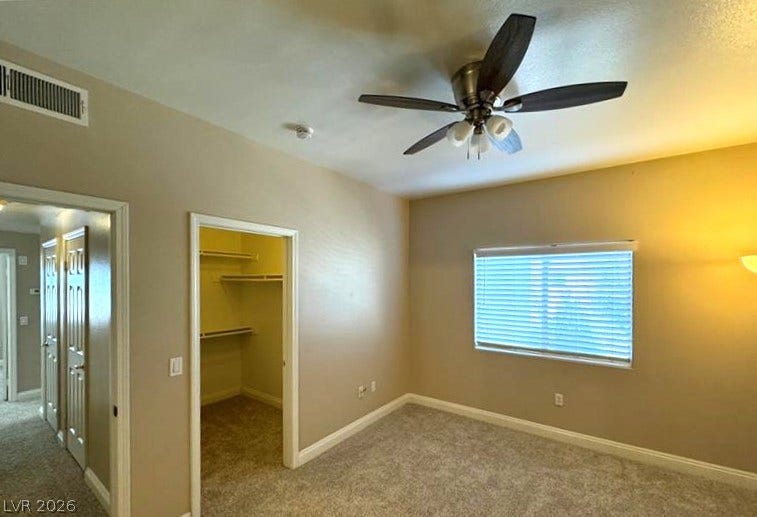 A spacious bedroom offers plush neutral carpeting and a dedicated walk-in closet.