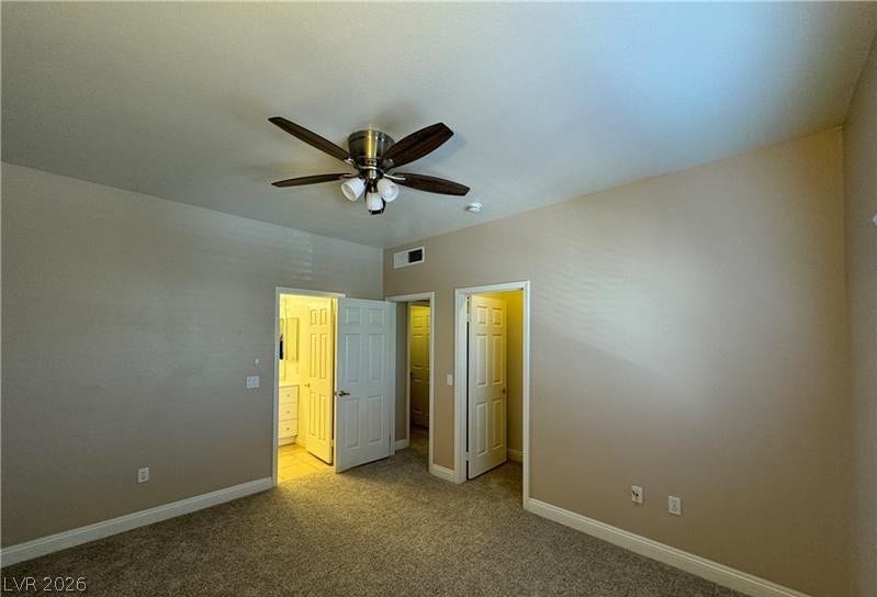 A spacious bedroom features wall-to-wall carpeting and multiple doorways leading to adjacent rooms.