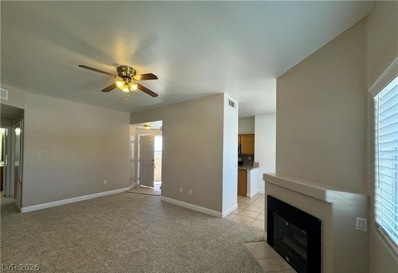 An open floor plan connects the carpeted living area to the adjacent kitchen.