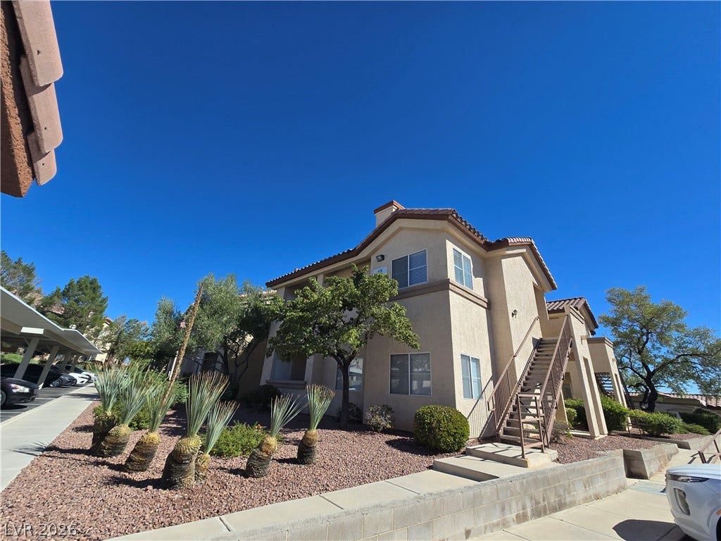 Stucco exteriors and tiled roofs define this multi-level residential building set against a clear blue sky.