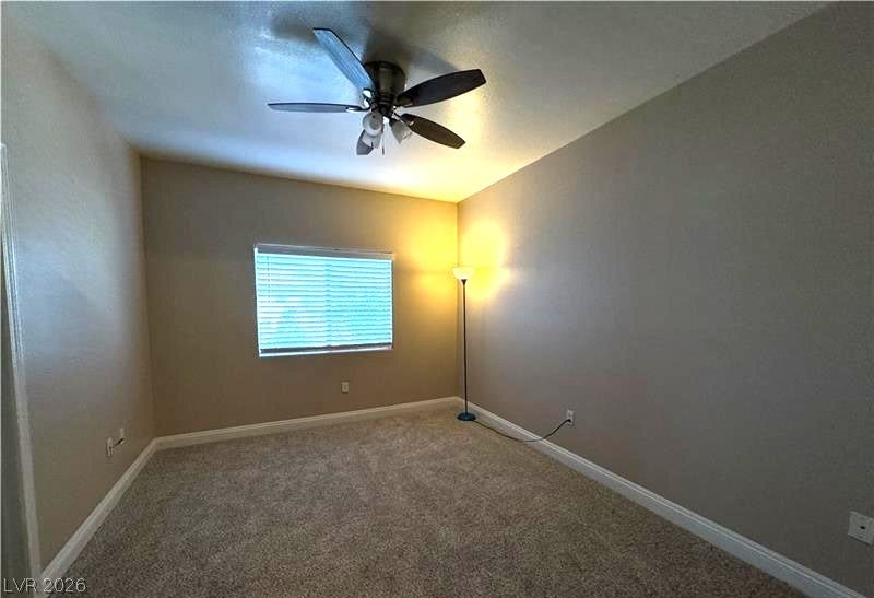 A spacious bedroom features comfortable neutral carpeting and a large window.