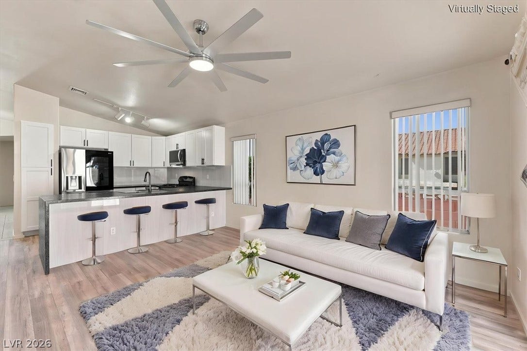 Virtually staged An open floor plan seamlessly connects the kitchen and main living space over wood-look flooring.