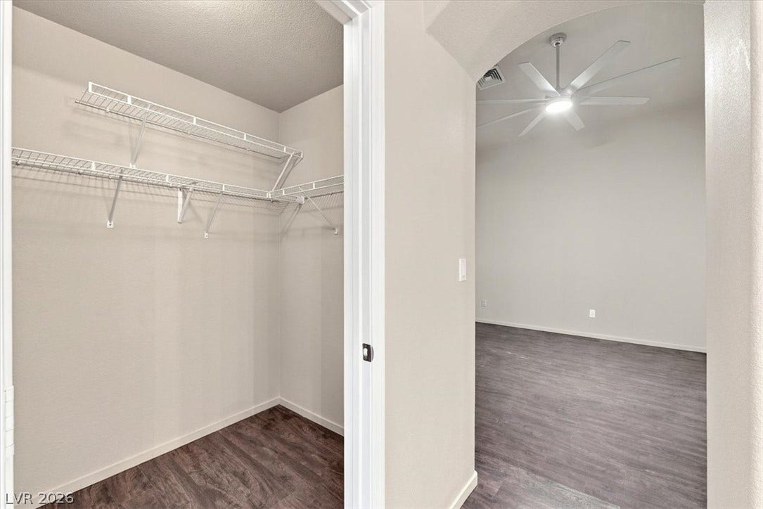 A spacious walk-in closet connects seamlessly to the main bedroom through an arched doorway.