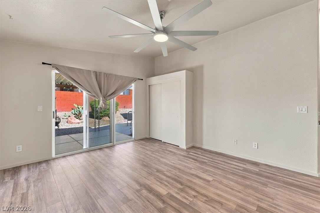 Sunlight streams across wood-look flooring from sliding glass doors opening to the patio.