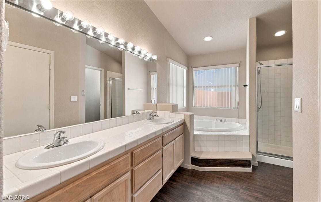An integrated soaking tub and separate walk-in shower complement the dual-sink vanity.