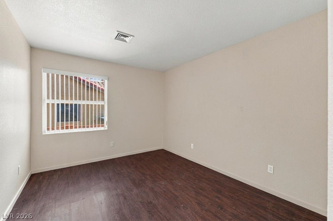 Rich wood-look flooring and a wide window with integrated blinds create a serene space.
