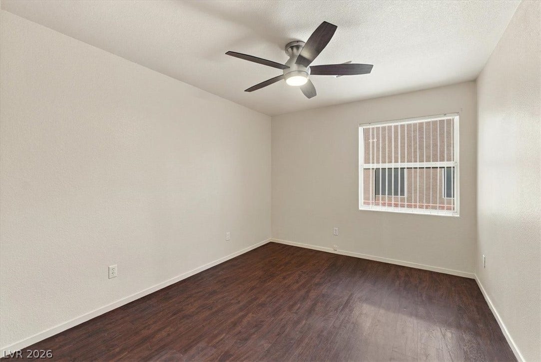 Rich dark wood floors ground this bedroom illuminated by a window.