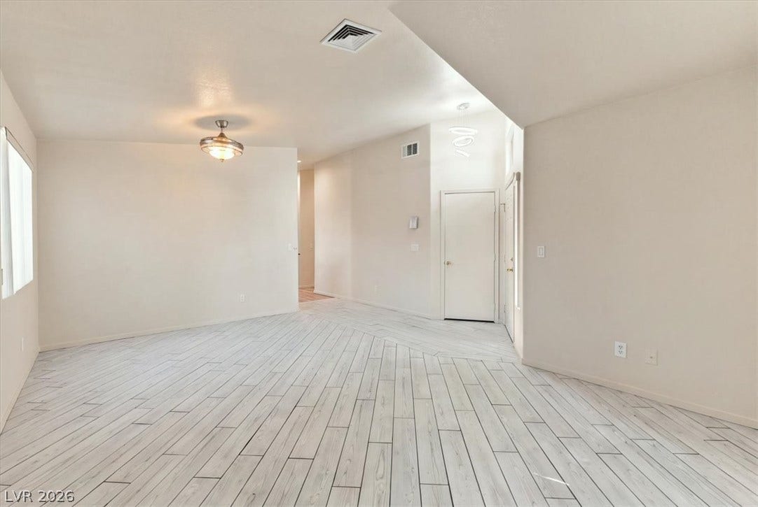 View of plank-style tile floors span this open entryway and living area with tall ceilings.