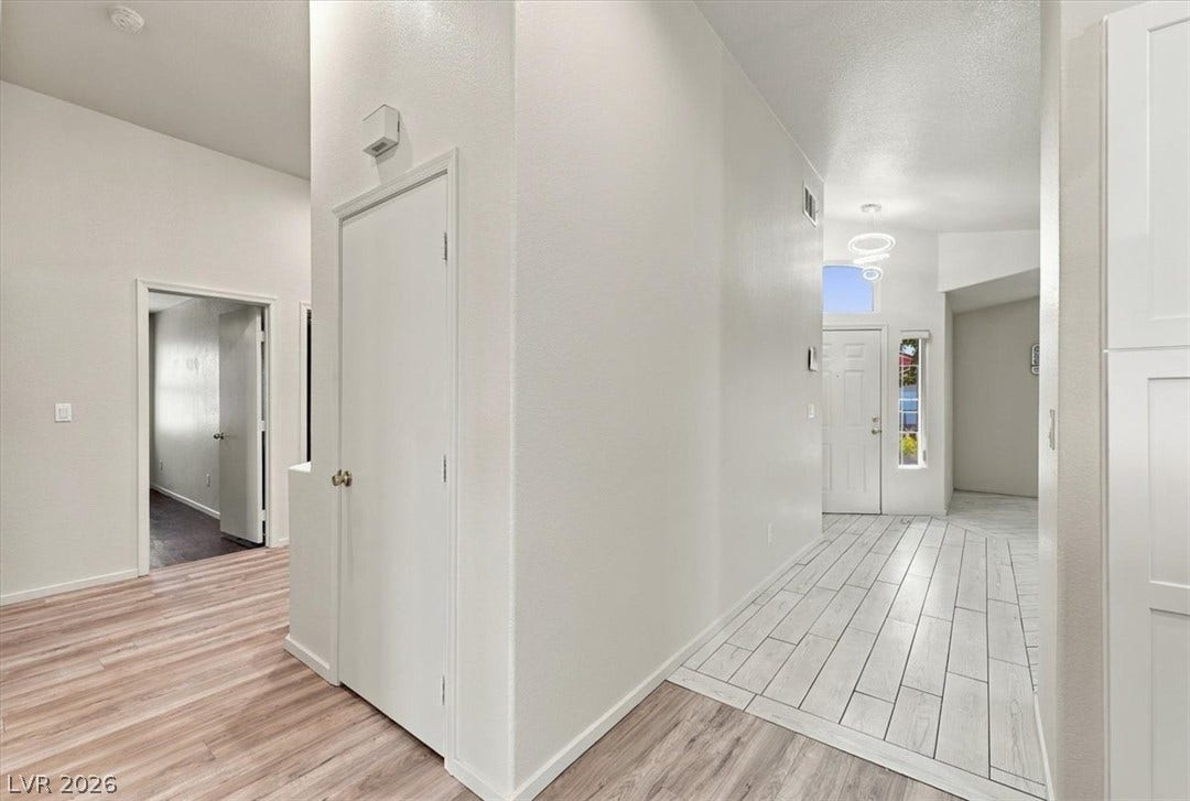An inviting entrance foyer transitions smoothly from tiled entry flooring to rich wood-look laminate.
