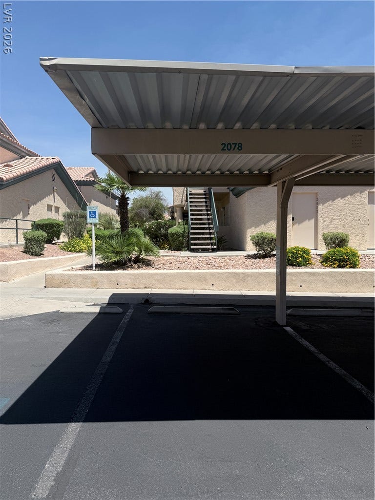 Convenient covered parking spaces provide shelter alongside neatly landscaped pedestrian walkways.