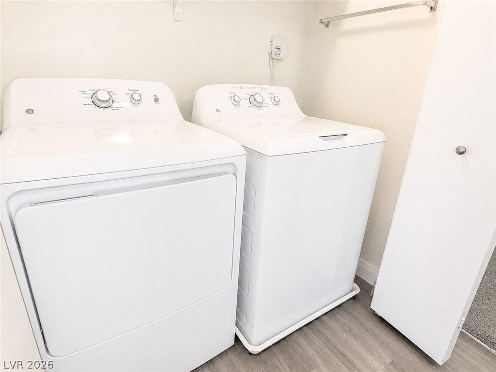 Functional laundry setup featuring durable flooring and a convenient storage closet.