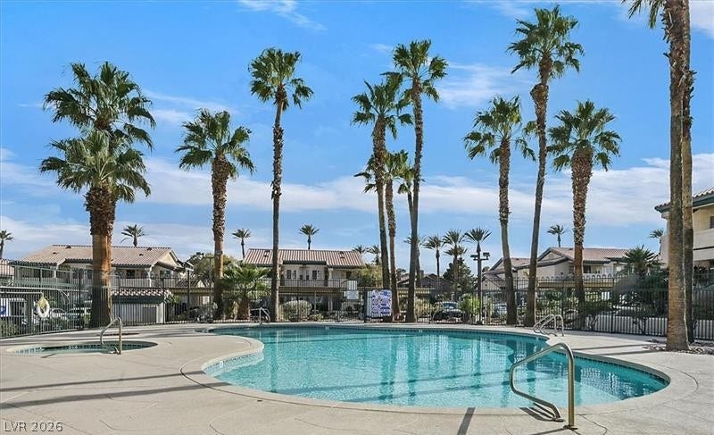 Towering palm trees frame a sparkling community swimming pool and adjacent spa.