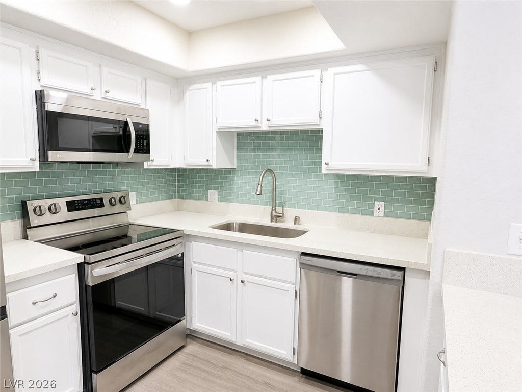 Crisp white cabinetry contrasts elegantly with a vibrant glass tile backsplash and modern finishes.