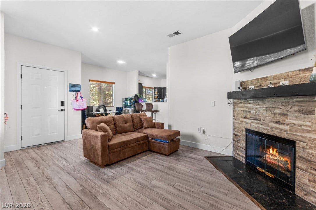5250 S Rainbow Boulevard, #2033, Las Vegas, NV 89118 Smooth wood-look flooring and a stone-faced fireplace anchor this inviting, open-concept living space.