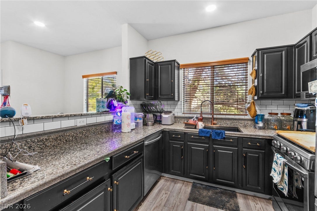 5250 S Rainbow Boulevard, #2033, Las Vegas, NV 89118 Dark cabinetry and granite counters define this kitchen featuring recessed lighting and wood-look flooring.