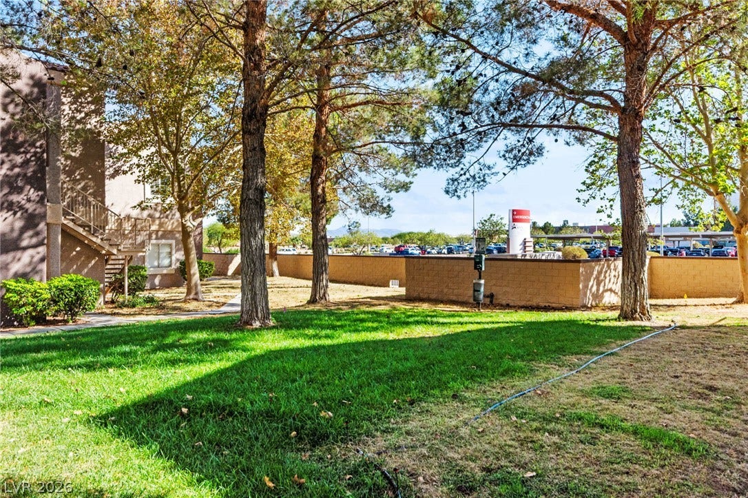 5250 S Rainbow Boulevard, #2033, Las Vegas, NV 89118 Mature trees shade a grassy lawn outside the stucco building complex.