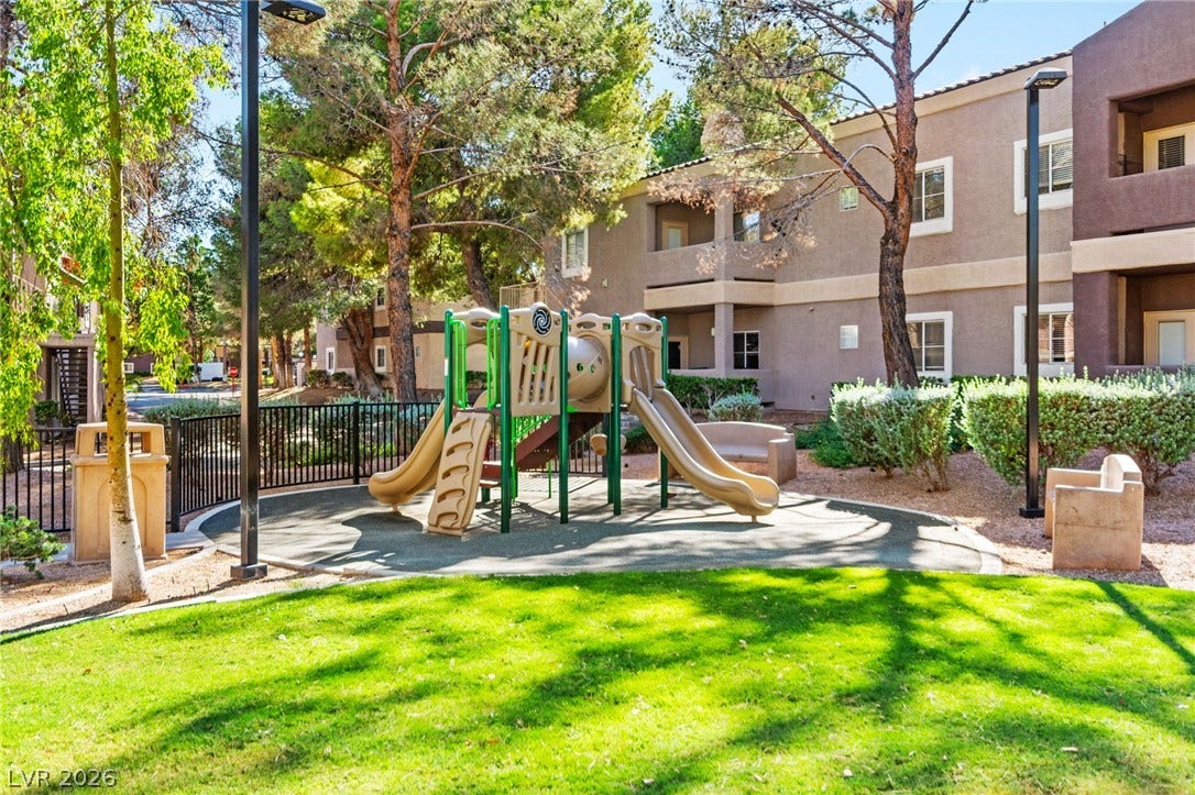 5250 S Rainbow Boulevard, #2033, Las Vegas, NV 89118 Mature trees shade a community playground set on lush green grass alongside residential buildings.