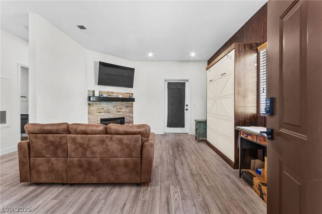 5250 S Rainbow Boulevard, #2033, Las Vegas, NV 89118 A stone fireplace accents this open living space featuring wide-plank wood flooring.