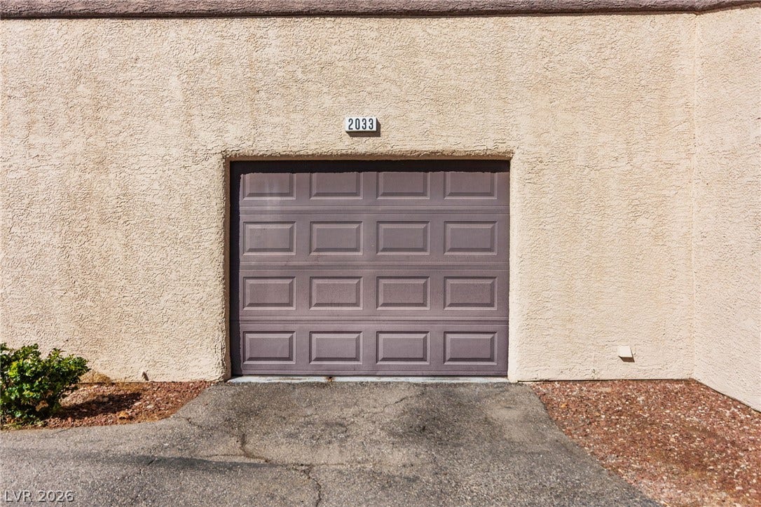 5250 S Rainbow Boulevard, #2033, Las Vegas, NV 89118 An attached single-car garage features a textured stucco exterior and paved driveway access.