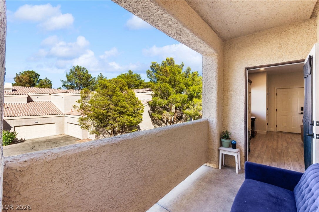 5250 S Rainbow Boulevard, #2033, Las Vegas, NV 89118 An elevated private balcony overlooks mature green trees and neighboring tiled roofs.