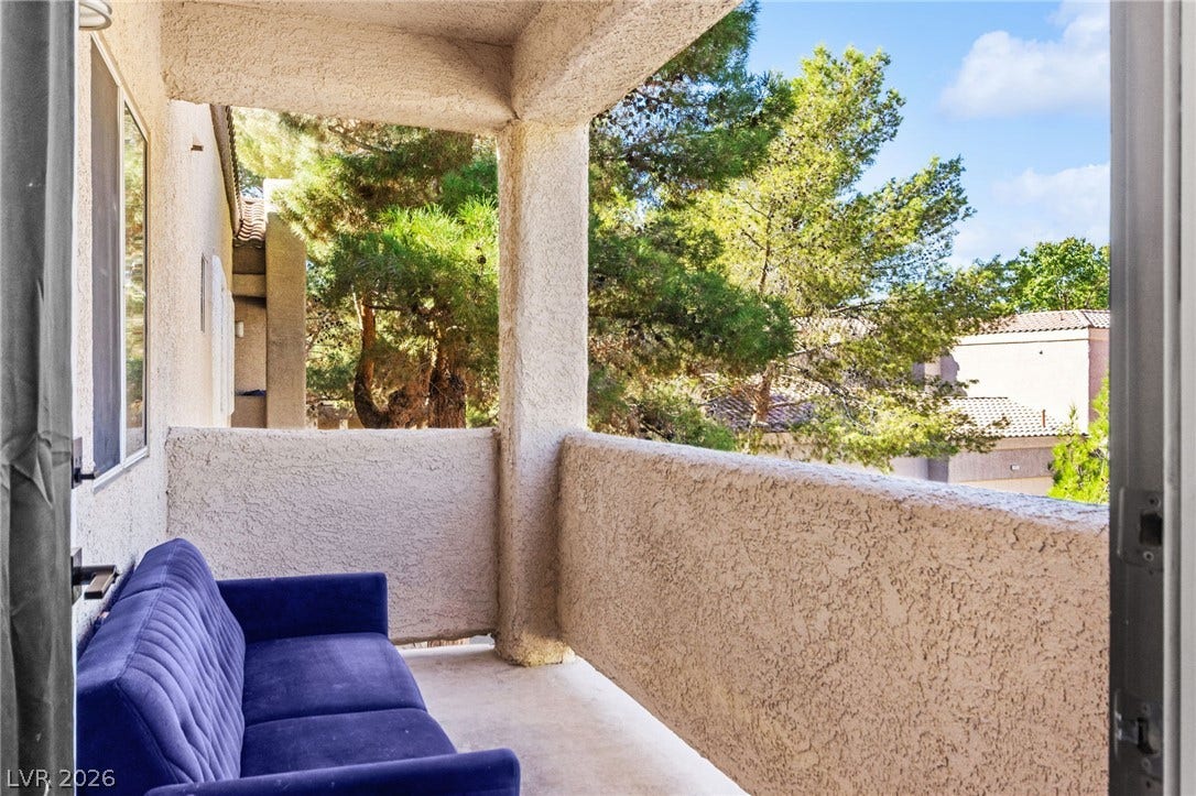 5250 S Rainbow Boulevard, #2033, Las Vegas, NV 89118 An inviting covered balcony features textured stucco finishes and views of mature green trees.