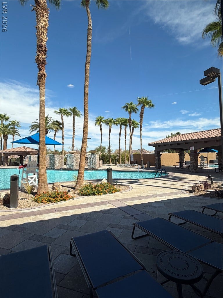 413 Via Gigante, Henderson, NV 89011 Lush palm trees and paved walkways surround the sparkling community pool under clear blue skies.