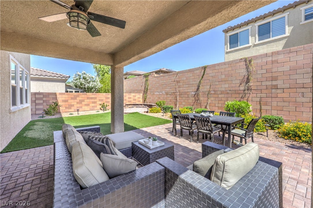 413 Via Gigante, Henderson, NV 89011 A private outdoor space with a comfortable seating area, a dining set, and neatly manicured turf.
