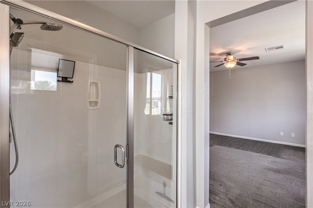 413 Via Gigante, Henderson, NV 89011 A spacious shower with modern fixtures offers a relaxing retreat adjacent to a cozy carpeted room.