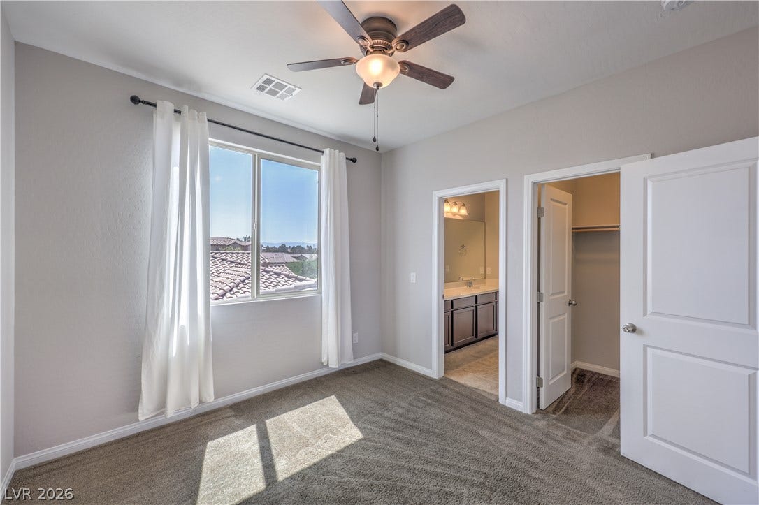 413 Via Gigante, Henderson, NV 89011 A comfortable bedroom features carpeted floors, a window with a view, and a convenient ceiling fan.