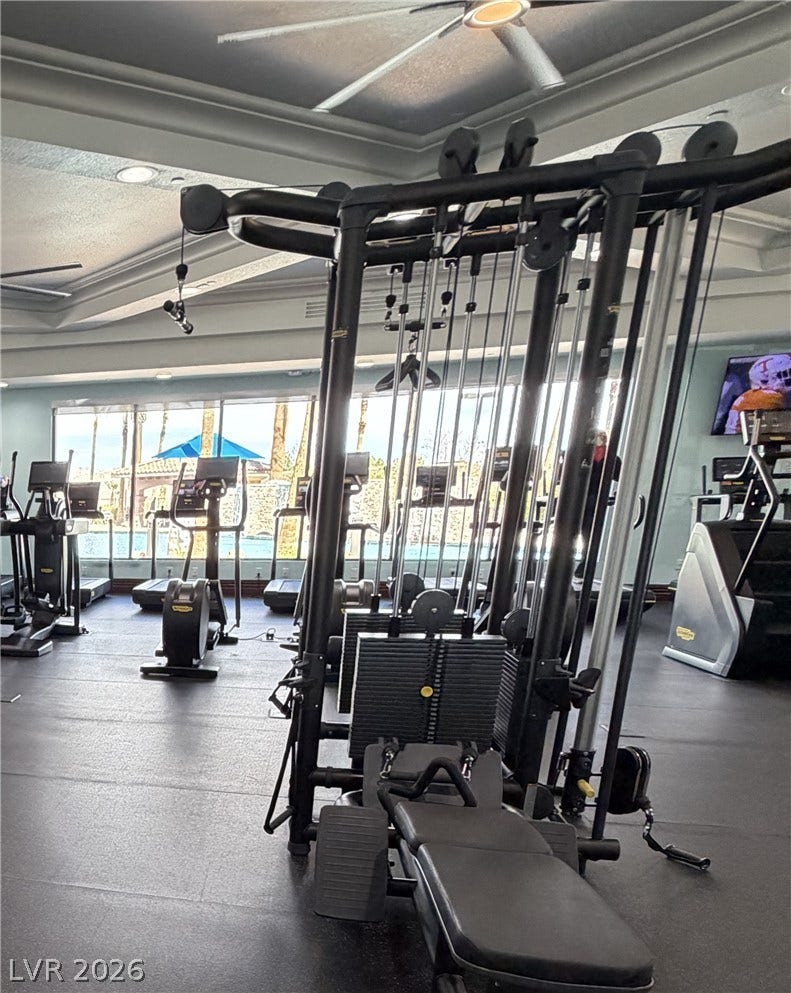 413 Via Gigante, Henderson, NV 89011 A spacious fitness facility features wall-to-wall windows looking out toward a pristine outdoor pool.
