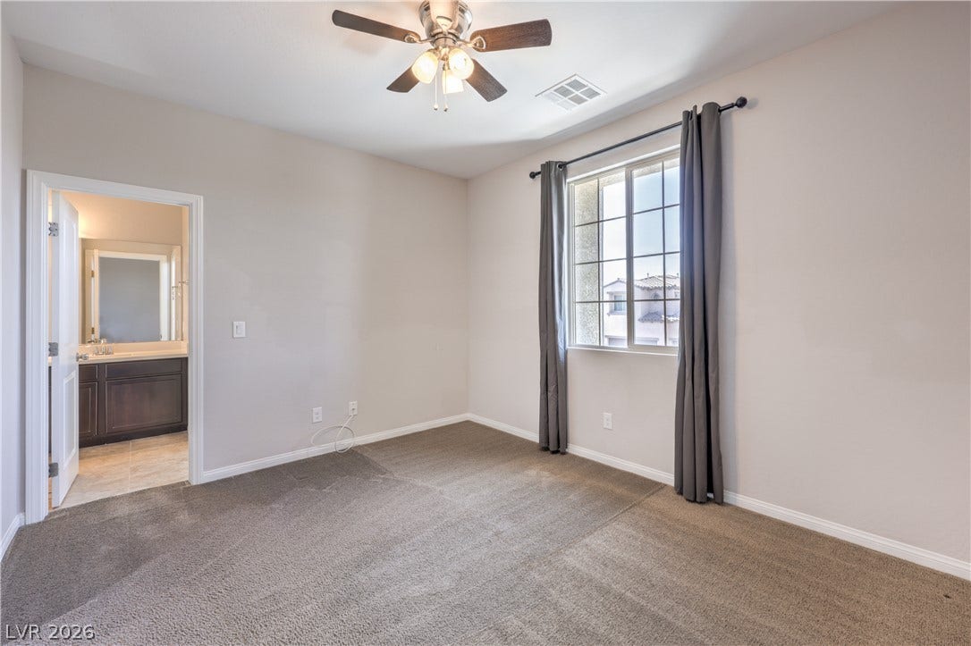 413 Via Gigante, Henderson, NV 89011 A well-lit bedroom features plush carpeting and convenient access to a private bathroom.