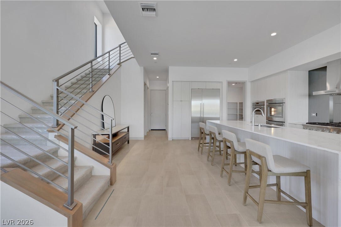 66 Lakefront Drive, Henderson, NV 89011 A striking contemporary open-concept space featuring a gourmet kitchen and sleek modern stair railing.