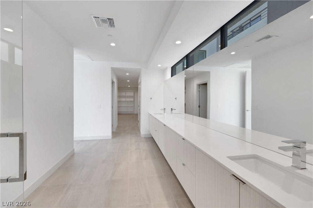 66 Lakefront Drive, Henderson, NV 89011 A well-lit primary bathroom showcases a lengthy vanity with dual sinks and expansive mirrors.
