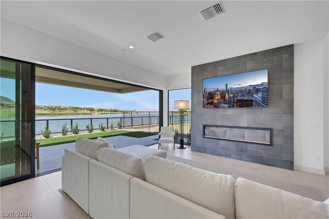 66 Lakefront Drive, Henderson, NV 89011 A spacious living area seamlessly blends indoor comfort with breathtaking water vistas, highlighted by a contemporary fireplace.