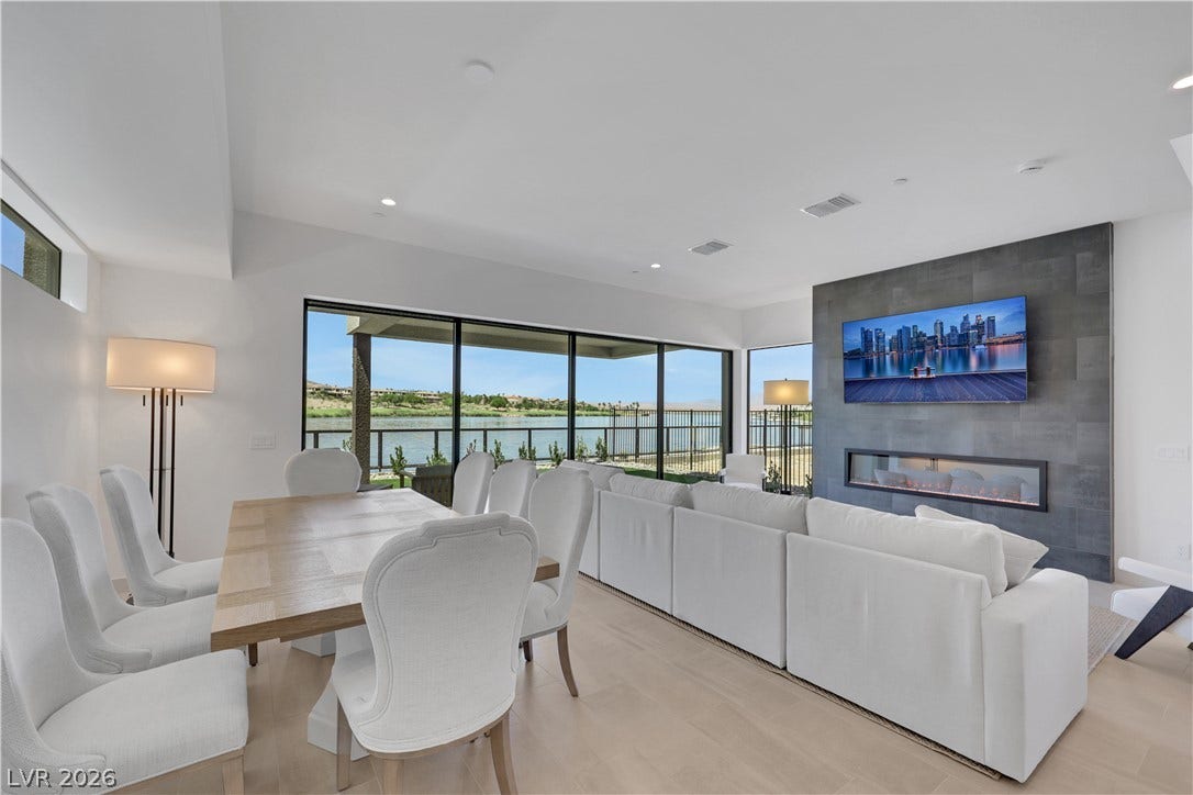 66 Lakefront Drive, Henderson, NV 89011 A spacious, airy living area offers serene water views and a sleek fireplace feature.
