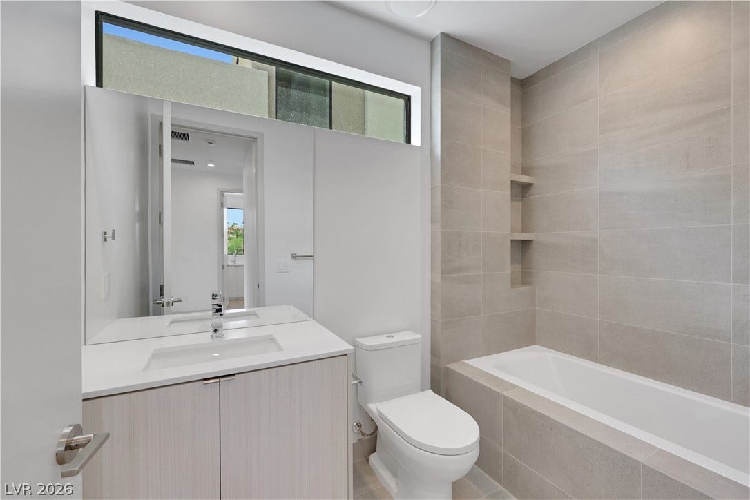 66 Lakefront Drive, Henderson, NV 89011 A well-lit bathroom features a modern vanity, a large tub, and tiled walls.