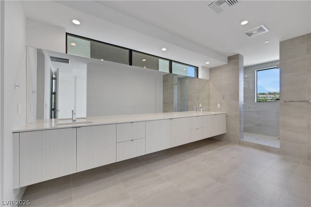 66 Lakefront Drive, Henderson, NV 89011 A spacious primary bath features an elongated floating double vanity and a glass-enclosed shower.