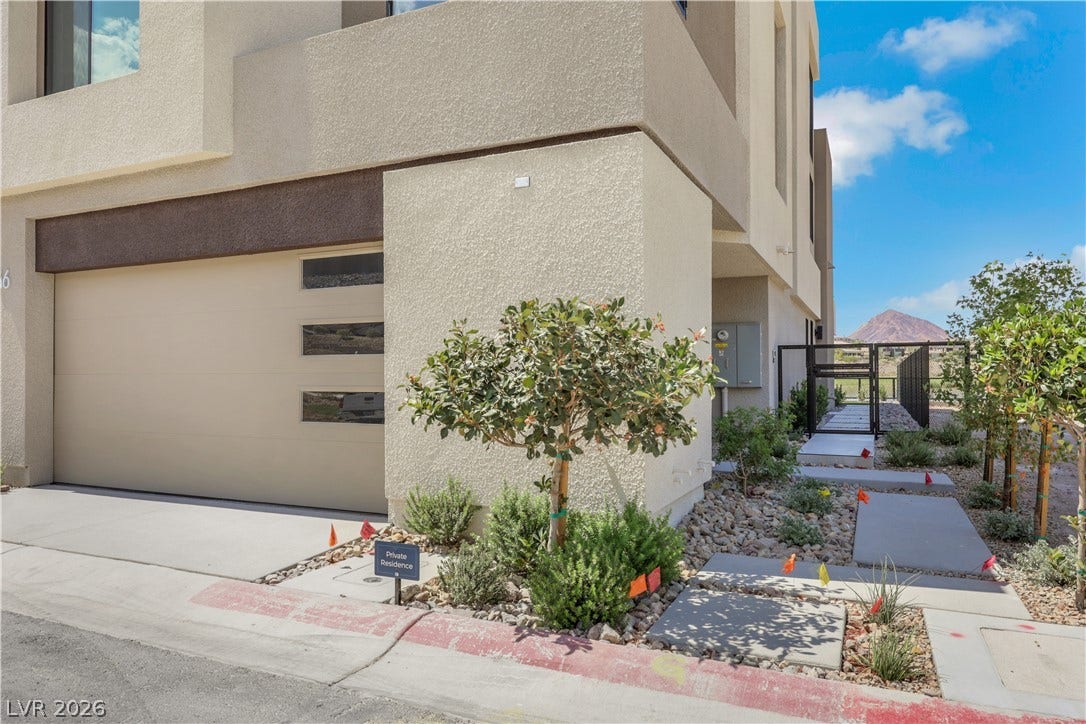 66 Lakefront Drive, Henderson, NV 89011 A modern facade with a well-maintained driveway and xeriscaped front yard, offering desert mountain views.