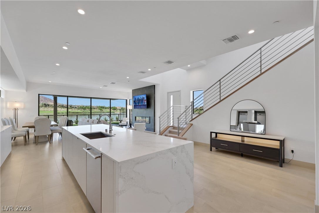 66 Lakefront Drive, Henderson, NV 89011 An open-concept living area boasts a sleek kitchen island, inviting fireplace, and a striking staircase with contemporary railings.