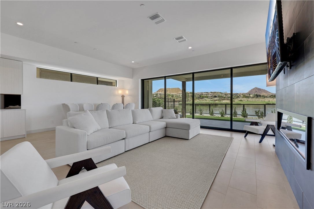 66 Lakefront Drive, Henderson, NV 89011 Floor-to-ceiling windows frame a mesmerizing lake and mountain vista, defining this elegant living space.
