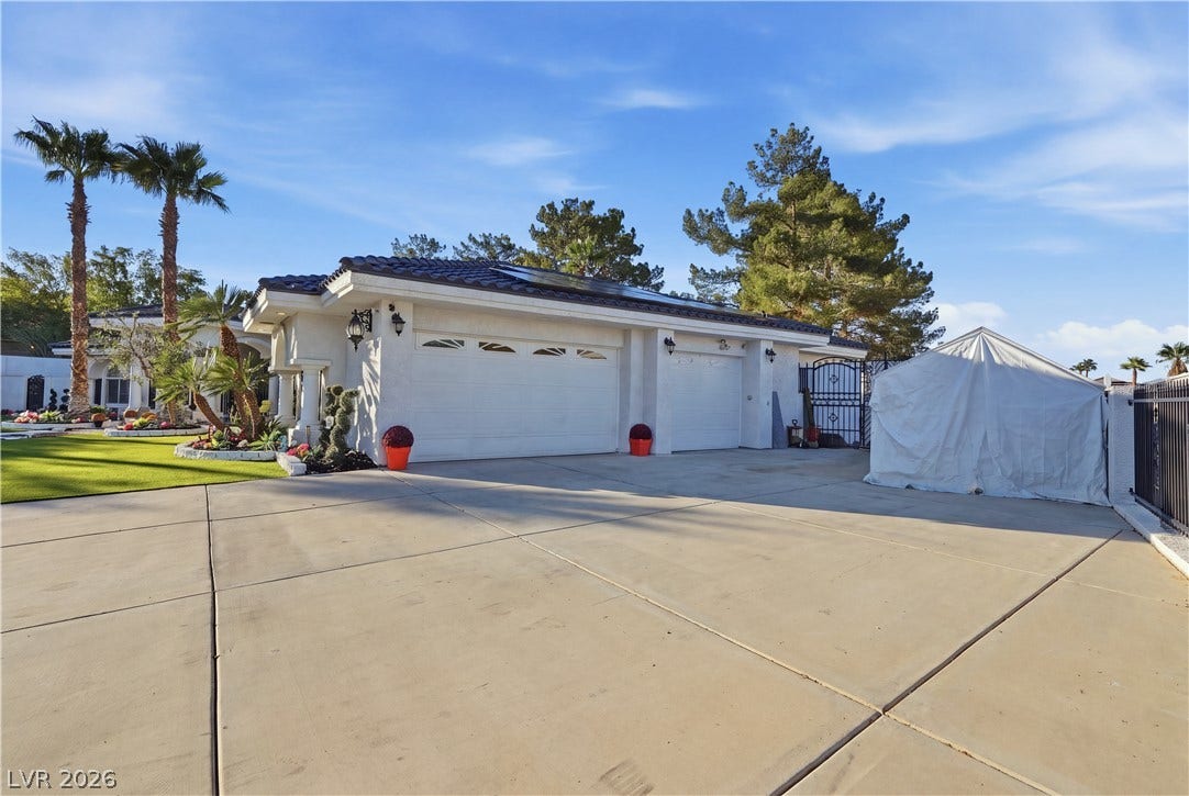 An expansive concrete driveway leads to the spacious attached garage of this stucco-finished home.