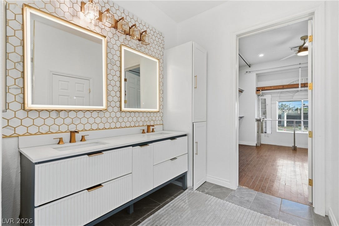 Geometric patterned tile backsplashes highlight a double vanity with stone counters and modern fixtures.