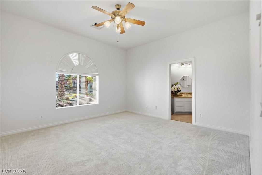An arched window and plush carpeting define this spacious main bedroom suite with adjacent bath.