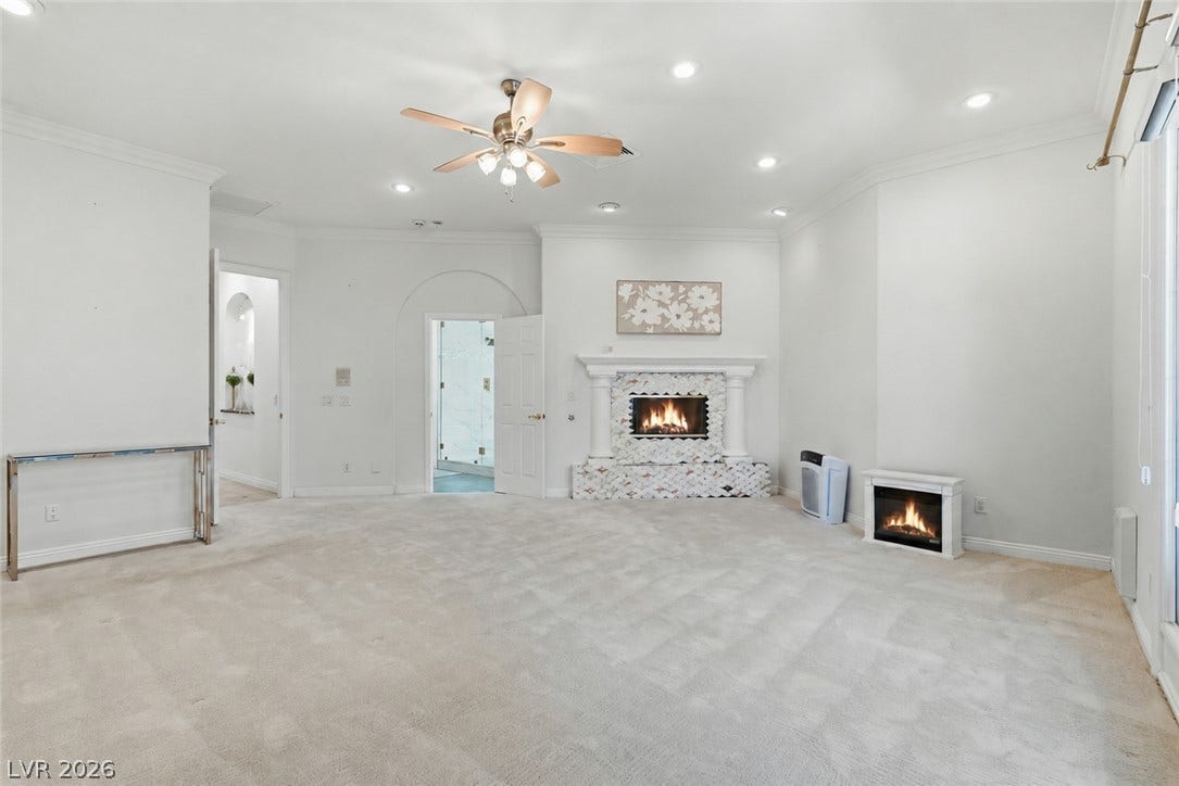 An elegant fireplace with classic detailing serves as the focal point of this spacious bedroom.
