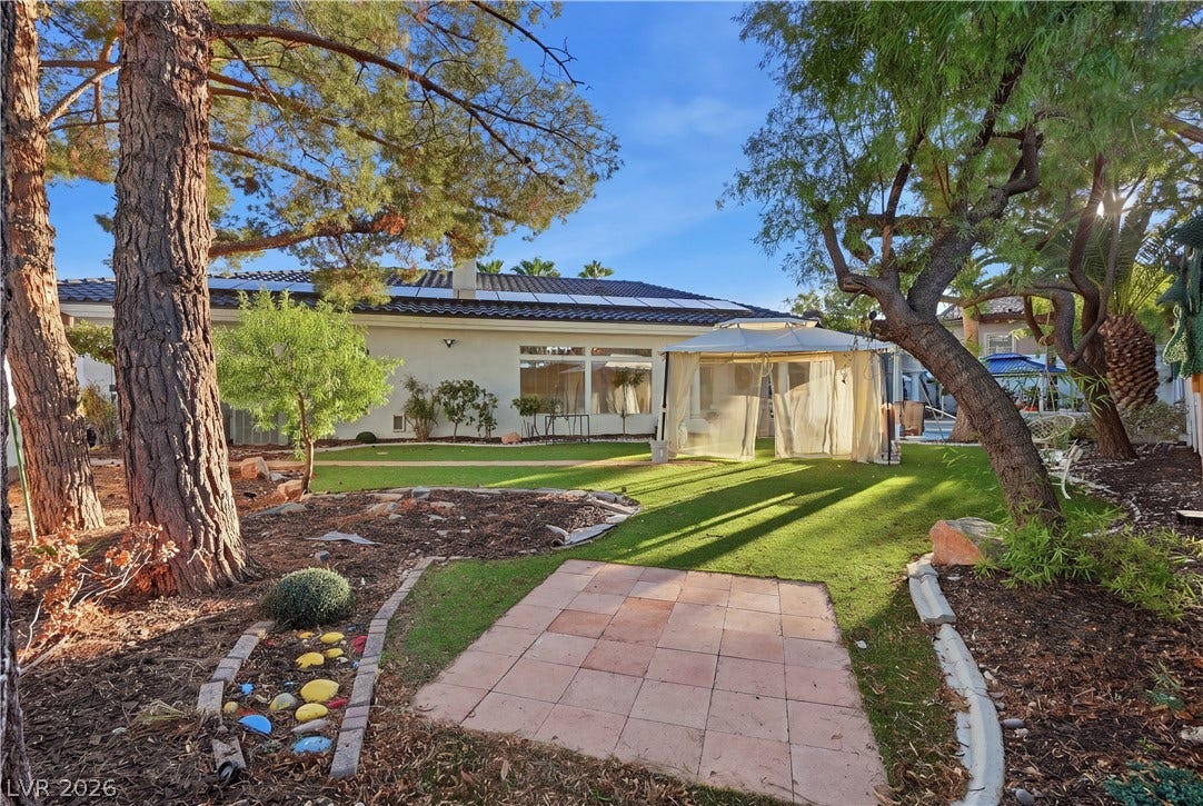 Mature trees shade a beautifully landscaped outdoor space complete with a gazebo and paved patio.