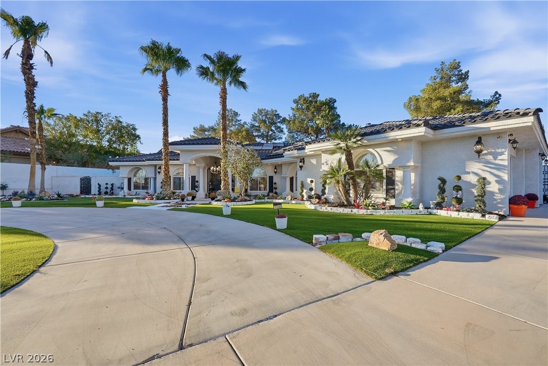 A sweeping circular driveway leads to this stucco exterior highlighted by tile roofing.